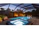 Charming screened-in pool area with a spa, fire bowls, lounge seating, and ambient lighting at dusk at 801 Seascape Pl, Sarasota, FL 34240