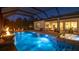 Stylish screened-in pool and spa with an outdoor dining and seating area, and elegant lighting at night at 801 Seascape Pl, Sarasota, FL 34240