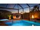 Tranquil screened-in pool area with a unique lounge, water feature, and lush landscaping at dusk at 801 Seascape Pl, Sarasota, FL 34240