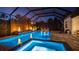 Beautiful screened-in pool area with a spa, water feature, lounge chairs, and inviting lighting at night at 801 Seascape Pl, Sarasota, FL 34240