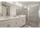 Bathroom featuring double sinks, white cabinetry, quartz countertops, and glass shower enclosure at 8612 Evening Dr, Sarasota, FL 34241