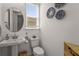 Clean half bathroom with a pedestal sink, white toilet, and basket decorations at 8612 Evening Dr, Sarasota, FL 34241