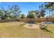 Large backyard featuring a fire pit area, lush lawn, and mature shady trees at 1010 Tropical Dr, Bradenton, FL 34208