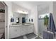 Bright main bathroom featuring a dual sink vanity, and a glass-enclosed shower with plants at 1010 Tropical Dr, Bradenton, FL 34208