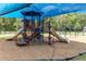 Playground with slides, stairs, and swings all on a wood chip ground covering and under a blue shade structure at 1034 Buttercup Gln, Bradenton, FL 34212