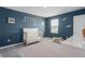 Bedroom featuring a crib, blue accent wall, carpet, and white trim at 10464 Ladybug Cv, Parrish, FL 34219