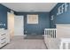 Bedroom featuring a crib, blue accent wall, carpet, and white trim at 10464 Ladybug Cv, Parrish, FL 34219