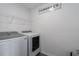 Well-lit laundry room featuring a modern washer and dryer, complemented by an overhead storage rack at 10464 Ladybug Cv, Parrish, FL 34219
