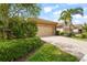 Charming home features a tan garage, paver driveway, lush landscaping, and a mature palm tree at 11959 Tapestry Ln, Venice, FL 34293