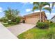 Charming home features a tan garage, paver driveway, landscaping, and a mature palm tree at 11959 Tapestry Ln, Venice, FL 34293