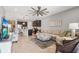 Open-concept living room with a large sectional sofa, ceiling fan, and a view of the kitchen with barstool seating at 11959 Tapestry Ln, Venice, FL 34293