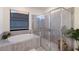 Modern bathroom featuring a soaking tub, glass-enclosed shower, and neutral tile at 17418 Blue Ridge Pl, Lakewood Ranch, FL 34211