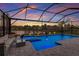 Inviting screened-in pool area featuring a spa, decorative lighting, and a view of the serene lake at 17418 Blue Ridge Pl, Lakewood Ranch, FL 34211