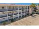 Low angle view of white condo with palm trees, dark railings, balconies, and parking spaces at 2008 Canal Dr # M3, Bradenton, FL 34207