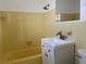Retro bathroom featuring a tub, toilet, and vanity with bright yellow tile creating a cheerful ambiance at 22343 Lasalle Rd, Port Charlotte, FL 33952