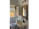 Updated bathroom featuring a pedestal sink, modern lighting and a stylish woven mirror at 4704 Winchester Dr, Sarasota, FL 34234