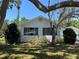 Well-lit exterior shot featuring a white home with large windows and an ample, tree-shaded front lawn at 4704 Winchester Dr, Sarasota, FL 34234