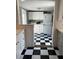 Galley kitchen includes ample white cabinets and black and white checkerboard tile floor at 4704 Winchester Dr, Sarasota, FL 34234
