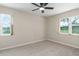 This bedroom features neutral walls, carpet flooring, and large windows showcasing the exterior landscaping at 5403 Red Rooster Rd, Parrish, FL 34219