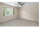 This bedroom features neutral walls, carpet flooring, a ceiling fan, and a window showcasing the exterior landscaping at 5403 Red Rooster Rd, Parrish, FL 34219