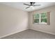 This bedroom features neutral walls, carpet flooring, a ceiling fan, and a window showcasing the exterior landscaping at 5403 Red Rooster Rd, Parrish, FL 34219