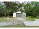 Detached two-car garage with a roll-up door, side door and a tractor outside at 5403 Red Rooster Rd, Parrish, FL 34219
