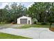 Detached two-car garage with a gray roll-up door, side door, and a tractor outside at 5403 Red Rooster Rd, Parrish, FL 34219