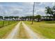 Scenic driveway leading to a well-maintained home with a beautiful lawn and a backdrop of mature trees at 5403 Red Rooster Rd, Parrish, FL 34219
