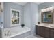 Bright bathroom featuring a soaking tub under a shuttered window and a wooden framed mirror above the vanity at 569 Mast Dr, Bradenton, FL 34208