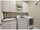 Organized laundry room with white cabinets and shelving above the sink and side by side washer and dryer at 569 Mast Dr, Bradenton, FL 34208