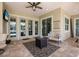 Covered outdoor patio with tile flooring, ceiling fan, comfortable seating around the fireplace, and access to the backyard at 569 Mast Dr, Bradenton, FL 34208