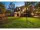 Spacious backyard with manicured lawn, mature trees, and inviting outdoor lighting, perfect for evening gatherings at 5716 Bayshore Blvd, Tampa, FL 33611