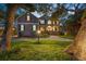 Elegant two-story home with a manicured lawn, mature trees, and inviting exterior lighting at 5716 Bayshore Blvd, Tampa, FL 33611