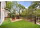 Inviting patio with artificial turf, lounge chairs, a stylish fire pit, and lush landscaping, perfect for outdoor relaxation at 5716 Bayshore Blvd, Tampa, FL 33611
