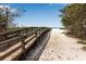 Scenic beach access via wooden boardwalk leading to sandy shores and tranquil ocean views under clear blue skies at 7030 Lois Ave, Longboat Key, FL 34228