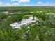 Aerial view of a modern luxury home nestled among mature trees and landscaping on large acreage at 7234 Letitia Ln, Sarasota, FL 34241