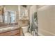 Well-lit bathroom featuring granite countertop, wooden cabinets, and tub with leaf-patterned shower curtain at 8352 Enclave Way # 104, Sarasota, FL 34243