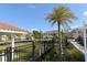 View of community from sidewalk with palms, manicured lawns, and fencing at 8352 Enclave Way # 104, Sarasota, FL 34243