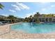 Community pool with poolside lounge area, palm trees, and clear blue water at 8352 Enclave Way # 104, Sarasota, FL 34243