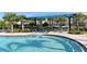 Inviting community pool with gradual entry, covered seating, and lush landscaping at 8352 Enclave Way # 104, Sarasota, FL 34243