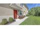 Attractive red front door entrance with stylish landscaping and a covered porch at 8352 Enclave Way # 104, Sarasota, FL 34243