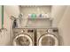Laundry room with stainless steel washer and dryer, wire shelving, and neatly arranged laundry supplies at 8352 Enclave Way # 104, Sarasota, FL 34243