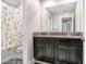 Bathroom with double vanity, granite countertop, dark cabinets, and shower with patterned curtain at 9646 Ivory Dr, Ruskin, FL 33573