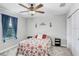 Well-lit bedroom features a ceiling fan, decorative wall art, and a window with blue curtains at 9646 Ivory Dr, Ruskin, FL 33573