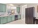 Stylish kitchen with sage-green cabinets, stainless steel appliances, tile flooring, and a pass-through to the living area at 9840 50Th Street E Cir, Parrish, FL 34219