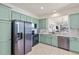 Modern kitchen boasts mint-green cabinets, stainless steel appliances, and an open layout with a view to the living space at 9840 50Th Street E Cir, Parrish, FL 34219