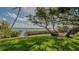 Backyard view with lush lawn, mature trees, and a glimpse of the waterfront at 1042 N Casey Key Rd, Osprey, FL 34229