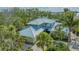 Beautiful two-story home featuring a well-manicured lawn and mature tropical landscaping with lush palm trees at 1042 N Casey Key Rd, Osprey, FL 34229