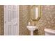 Elegant powder room with decorative wallpaper, a pedestal sink, and a classic white door at 1042 N Casey Key Rd, Osprey, FL 34229