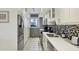Galley kitchen featuring stainless steel appliances, mosaic tile backsplash, and white cabinetry at 1065 Gulf Of Mexico Dr # 103, Longboat Key, FL 34228
